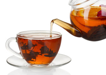 Glass teapot pouring black tea into cup isolated on white