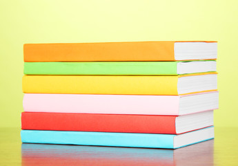 Stack of multicolor books   on green background