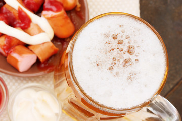 Beer and grilled sausages on wooden background
