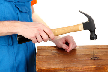 Builder hammering nails into board isolated on white