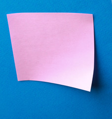 Pink paper note on blue background isolated.