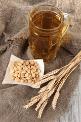 Beer in glass and nuts on bagging on wooden table