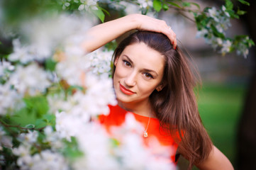 Naklejka premium Young woman in red dress walking in garden