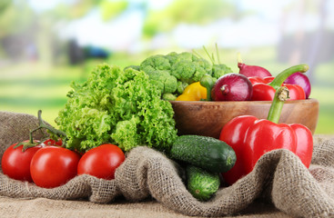 Fresh vegetables on burlap on bright background