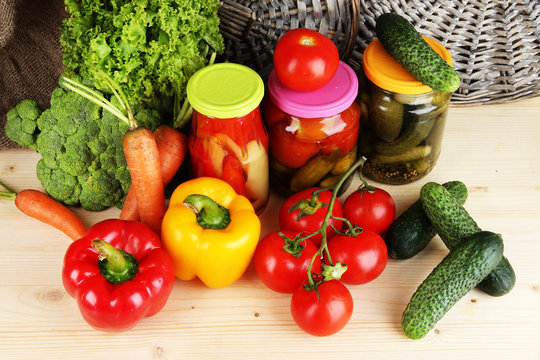 Fresh vegetables and canned on wooden table close up