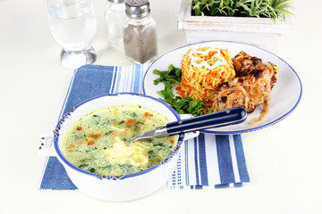 Soup and rice with meat in plates on napkin on table