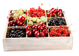 Different summer berries in wooden crate isolated on white