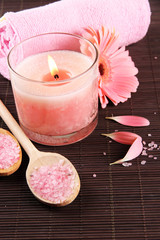 Beautiful pink candle with flower and towel on bamboo mat