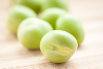 Green peas on wooden board. Shallow depth of field.