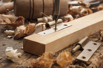 close up  of a carpenter screwed a hinge on a wooden plank