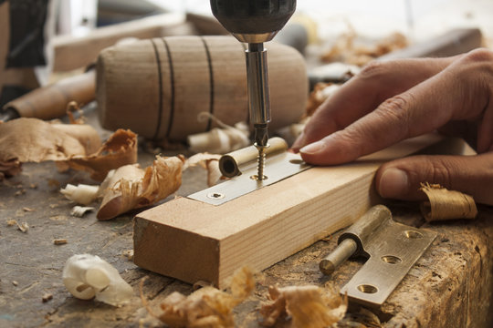 close up  of a carpenter screwed a hinge on a wooden plank