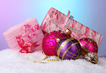 beautiful Christmas balls and gifts on snow on bright
