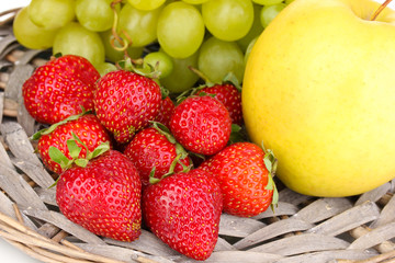 ripe sweet fruits and berries on wicker mat close-up
