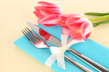 Festive dining table setting with tulips on beige background