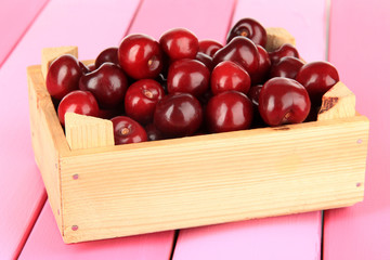 Cherry berries in wooden box on wooden table close-up