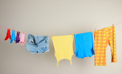 Laundry line with clothes on wall background