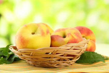 Ripe sweet peaches in basket on table, outdoors