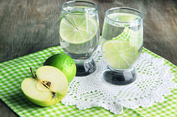 Fototapeta na wymiar Glasses of cocktail with lime on napkin on dark wooden table