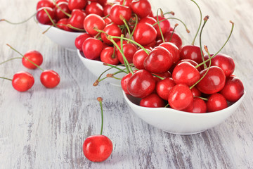 Cherry berries in bowl on wooden table close up