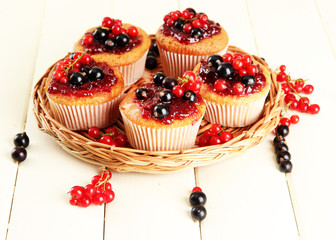 Tasty muffins with berries on white wooden table