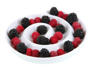 Ripe raspberries and blackberries in plate isolated on white