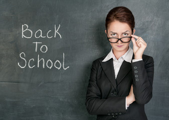 Teacher and phrase Back to school on the school blackboard