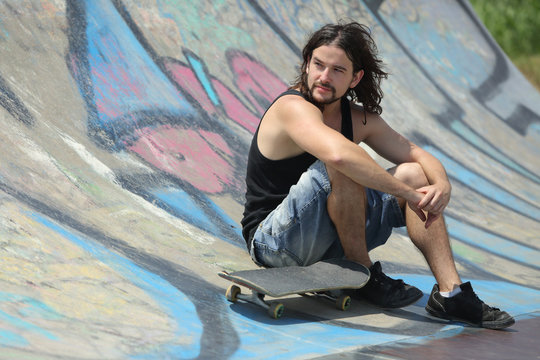 Boy sitting with a skateboard on a half pipe