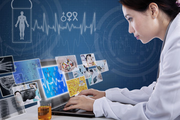 Busy doctor typing on laptop with digital pictures