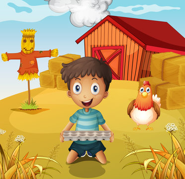 A boy holding an empty egg tray at the farm with a scarecrow