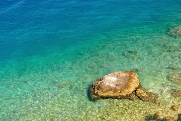 Amazing beach in adriatic sea with big stone. Podgora, Croatia
