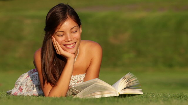 Girl reading book in park smiling happy