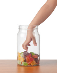 Child's hand reaching out to take candy from a jar