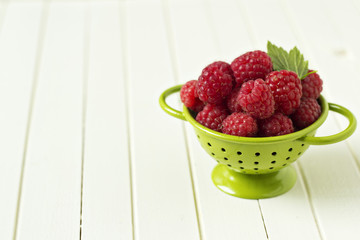 Fresh raspberries in green colander