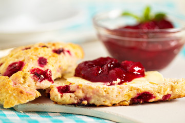 Scone with orange zest and berries with butter and jam