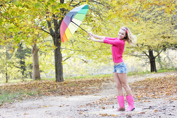 young happy woman with colorful umbrella in autumn park