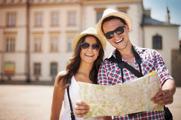 Happy tourists couple holding map - obrazy, fototapety, plakaty