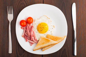 Fried egg with toasts, ham and cherry tomato