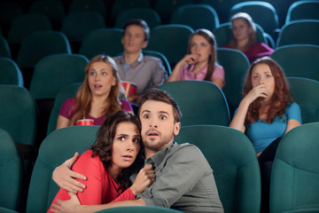 Horror movie. Terrified young couple hugging while watching movi