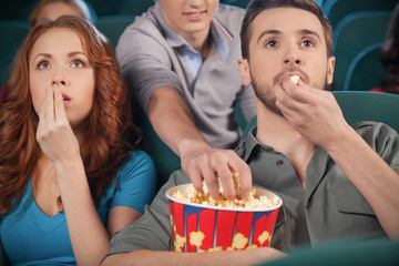 Stealing popcorn. Young men stealing popcorn during the movie se