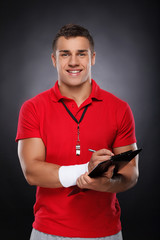 Young Coach. Portrait of cheerful young coach holding a clipboar