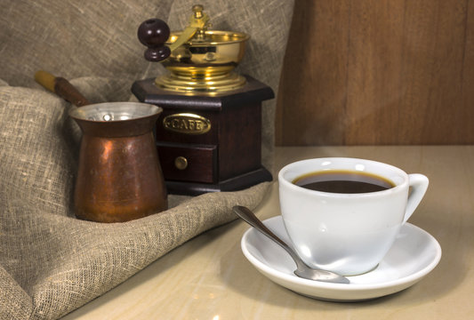 Coffee in a cup on a marble table, hand-mill and Cezve