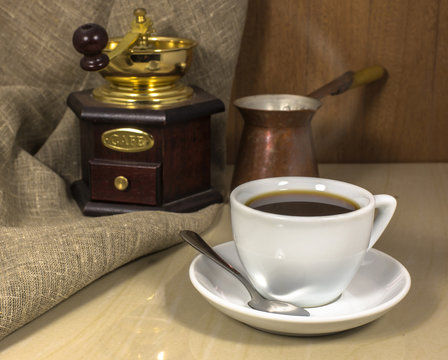 Coffee in a cup on a marble table, hand-mill and Cezve
