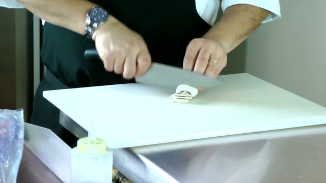 the hands of a man slicing a mushroom with a kitchen