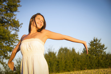 Fototapeta premium woman standing in wheat field at sunset