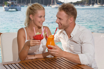 Junges Paar im Urlaub am Meer trinkt einen Cocktail