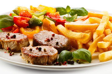 Grilled steaks, French fries and vegetables