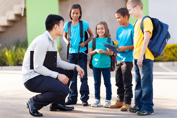 elementary pupils outside classroom talking to teacher