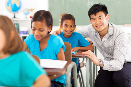 Primary Teacher Helping Student In Classroom