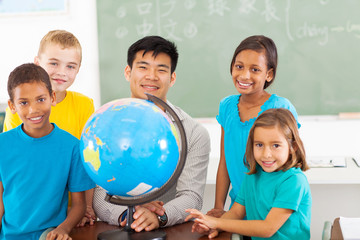 primary school geography teacher and students with a globe