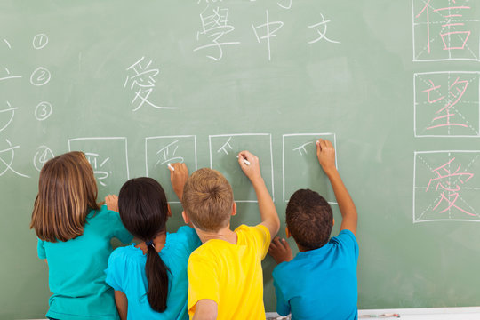 rear view of students learning chinese writing on chalkboard